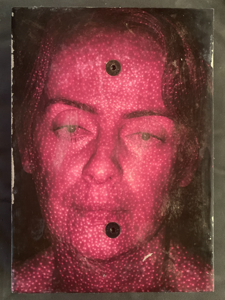 A red photograph of a human face covered in small bright dots